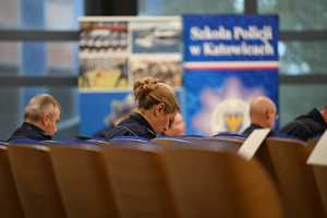 umundurowani policjanci i policjantki siedzą na krzesłach w auli