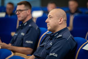 umundurowani policjanci i policjantki siedzą na krzesłach w auli