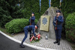 Zdjęcie policjanta składającego kwiaty przy pomniku