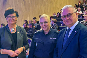 zdjęcie przedstawia trzy osoby, jedna kobieta jest w mundurze