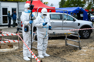 zdjęcie przedstawia policjantów w ochronnych kombinezonach dokonujących oględzin na miejscu katastrofy w trakcie ćwiczeń.