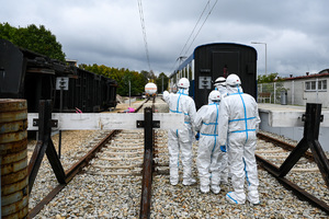 zdjęcie przedstawia policjantów w ochronnych kombinezonach dokonujących oględzin na miejscu katastrofy w trakcie ćwiczeń.