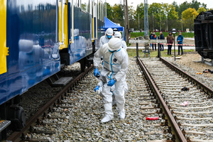 zdjęcie przedstawia policjantów w ochronnych kombinezonach dokonujących oględzin na miejscu katastrofy w trakcie ćwiczeń.