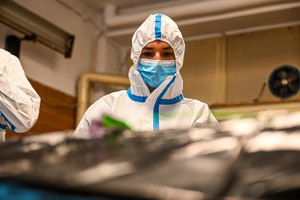 zdjęcie przedstawia policjantkę w kombinezonie ochronnym w trakcie oględzin manekina imitującego ofiarę katastrofy.