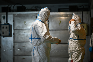 zdjęcie przedstawia policjantów w ochronnych kombinezonach w prosektorium.