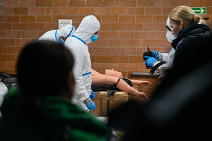 zdjęcie przedstawia policjantów w ochronnych kombinezonach w trakcie oględzin manekina imitującego ofiarę katastrofy.