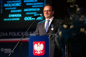 zdjęcie przedstawia mężczyznę przemawiającego ze sceny.
