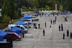 Zdjęcie parkingu na którym znajdują się pojazdy i policjanci