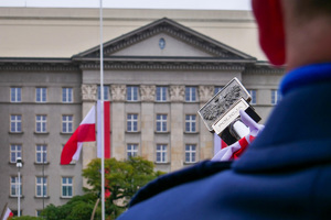 umundurowany policjant obok sztandaru z godłem RP