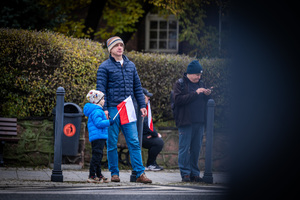Zdjęcie przedstawia mężczyznę z chłopcem, który w ręku trzyma flagę Polski.