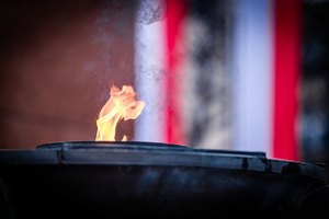 palący się znicz na tle flag RP