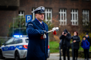 umundurowany policjant na tle radiowozu z włączonymi sygnałami świetlnymi