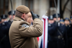 salutujący żołnierz przy fladze RP