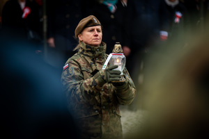 żołnierka trzymająca w ręku zapalony znicz