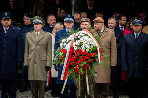 Komendant Wojewódzki Policji w Katowicach obok innych policjantów, żołnierzy i wieńca kwiatów