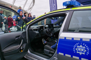 cywile oglądają policyjny radiowóz, w którym siedzi dziecko