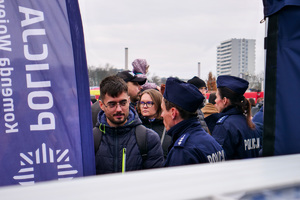 policjanci obok policyjnego stoiska w towarzystwie cywilów