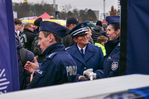 policjanci z cywilami obok policyjnego stoiska promocyjnego