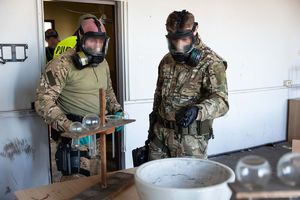 policjanci w maskach przeciwgazowych w pomieszczeniu z wieloma naczyniami