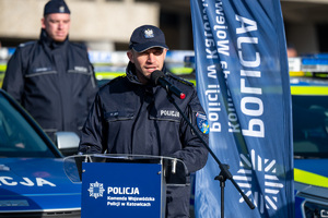 fotografia przedstawia policjantów na tle radiowozów