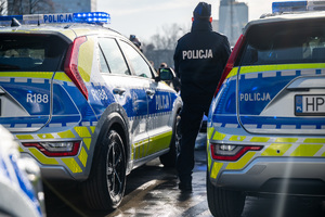 policjant stojący obok nowych radiowozów