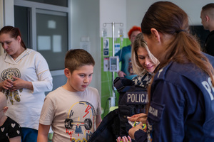 policjantka rozdaje odblaskowe zawieszki w placówce medycznej