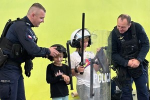 na zdjęciu umundurowani policjanci i uczestniczące w prelekcji dzieci, którzy prezentują wyposażenie