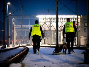 Policjant oraz funkcjonariusz SOK z psem przy torach w trakcie patrolowania torów kolejowych