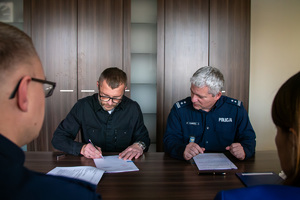 zdjęcie przedstawia zastępcę komendanta i mężczyznę podpisującego dokumenty