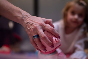 zdjęcie przedstawia dłoń z pomalowanymi paznokciami, biżuterią, która trzyma pluszowy przedmiot.