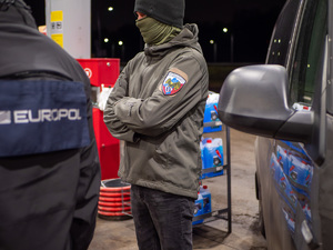 zdjęcie przedstawia dwóch funkcjonariuszy stojących obok samochodu.