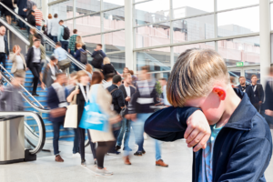 Smutny chłopiec wycierający łzy w rękaw w centrum handlowym pełnym ludzi.