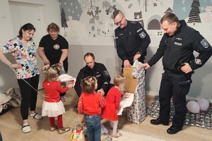 Policjanci pomagają dzieciom rozpakować prezent.