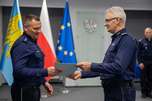 Komendant Wojewódzki Policji w Katowicach wręcza dokument policjantowi.