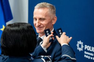 Na zdjęciu widoczny policjant, któremu zmieniane są dystynkcje