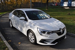 Biały samochód marki Renault stojący na wąskiej asfaltowej drodze.