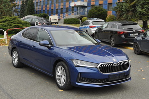 Granatowy samochód marki skoda stojący przed budynkiem KWP w Katowicach.