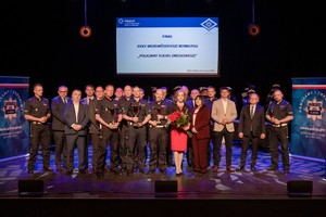 Policjanci na scenie stojący w towarzystwie elegancko ubranych kobiet i mężczyzn.