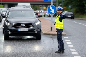 Policjantka ruchu drogowego na jezdni ręcznie kieruje ruchem.