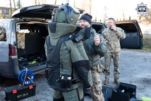 na zdjęciu umundurowani policjanci stoją przy otwartych bagażnikach pojazdów policyjnych