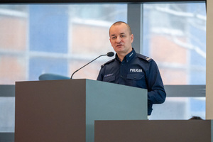 Na zdjęciu widoczny umundurowany policjant, który przemawia na mównicy.