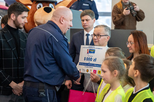 Na zdjęciu widoczny Zastępca Komendanta Wojewódzkiego Policji w Katowicach inspektor Jacek Stelmach, który wręcza nagrodę dzieciom i opiekunowi.