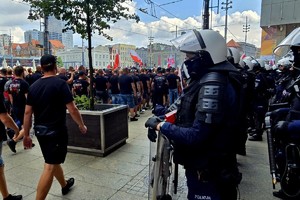 na zdjęciu umundurowani policjanci przyglądają się grupie maszerujących ludzi