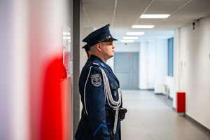 Zbliżenie na policjantów pełniących wartę honorową przed tablicą upamiętniającą postać insp. dr Adama Kocura.