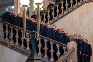 Na zdjęciu widoczni umundurowani policjanci stojący na schodach w reprezentacyjnym westybulu Śląskiego Urzędu Wojewódzkiego w Katowicach.