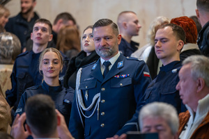 Na zdjęciu widoczny policjant w mundurze galowym, stojący pomiędzy policjantką i policjantem.
