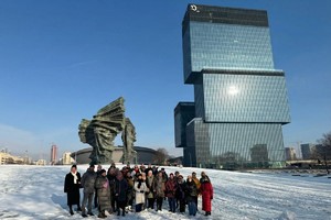 Grupa kobiet stoi na tle pomnika i budynku.