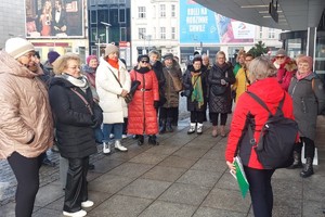 Grupa kobiet stoi na chodniku przed wejściem do budynku.
