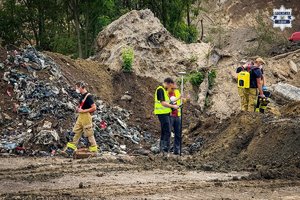 Na zdjęciu widać wysypisko śmieci oraz strażaków pracujących na jego terenie.
