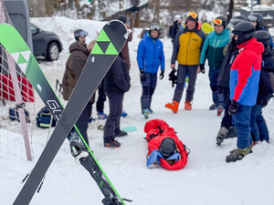 grupa osób stoi wokół leżącego na ziemi poszkodowanego.